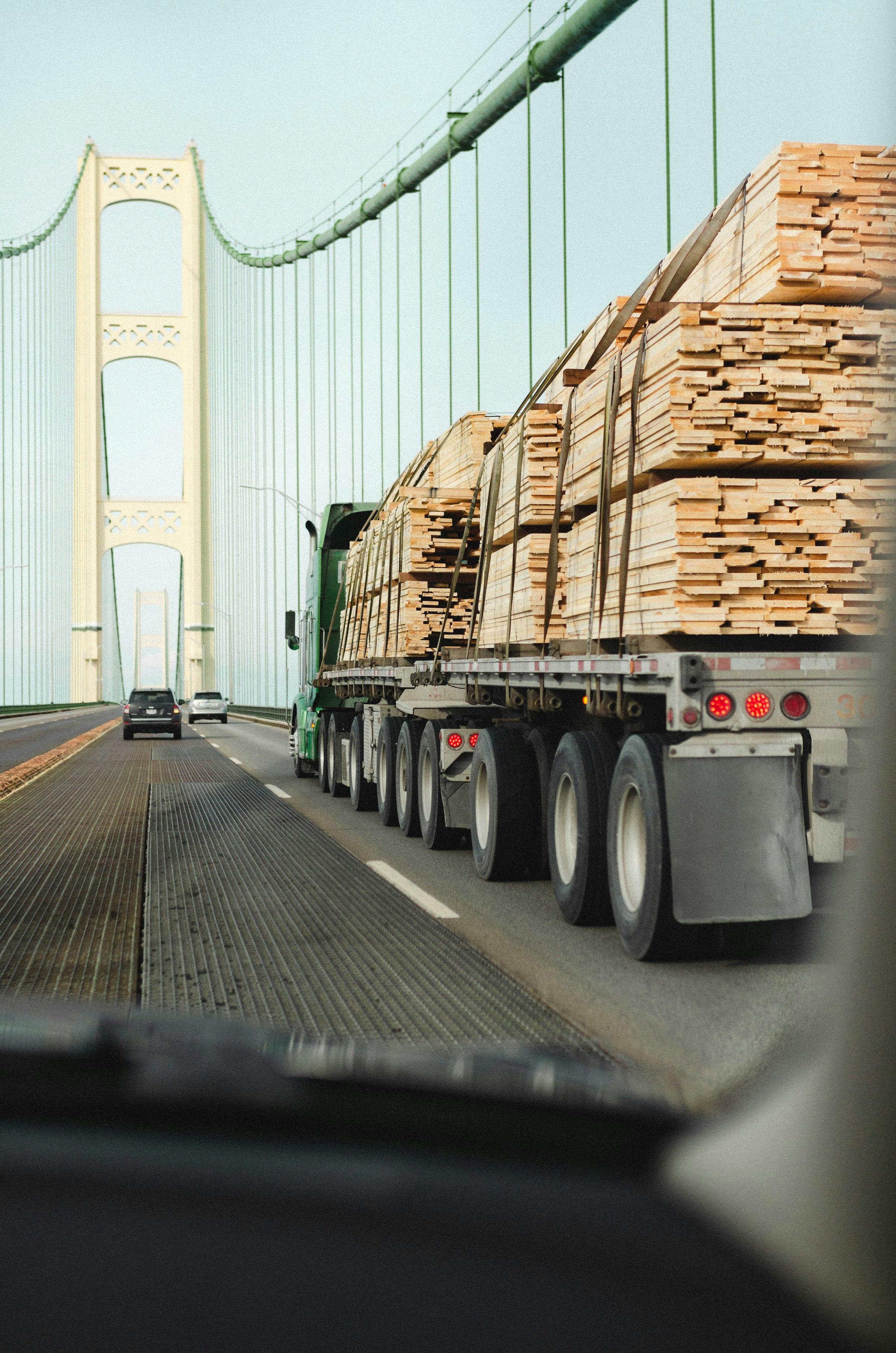 Flatbed truck hauling lumber across a bridge